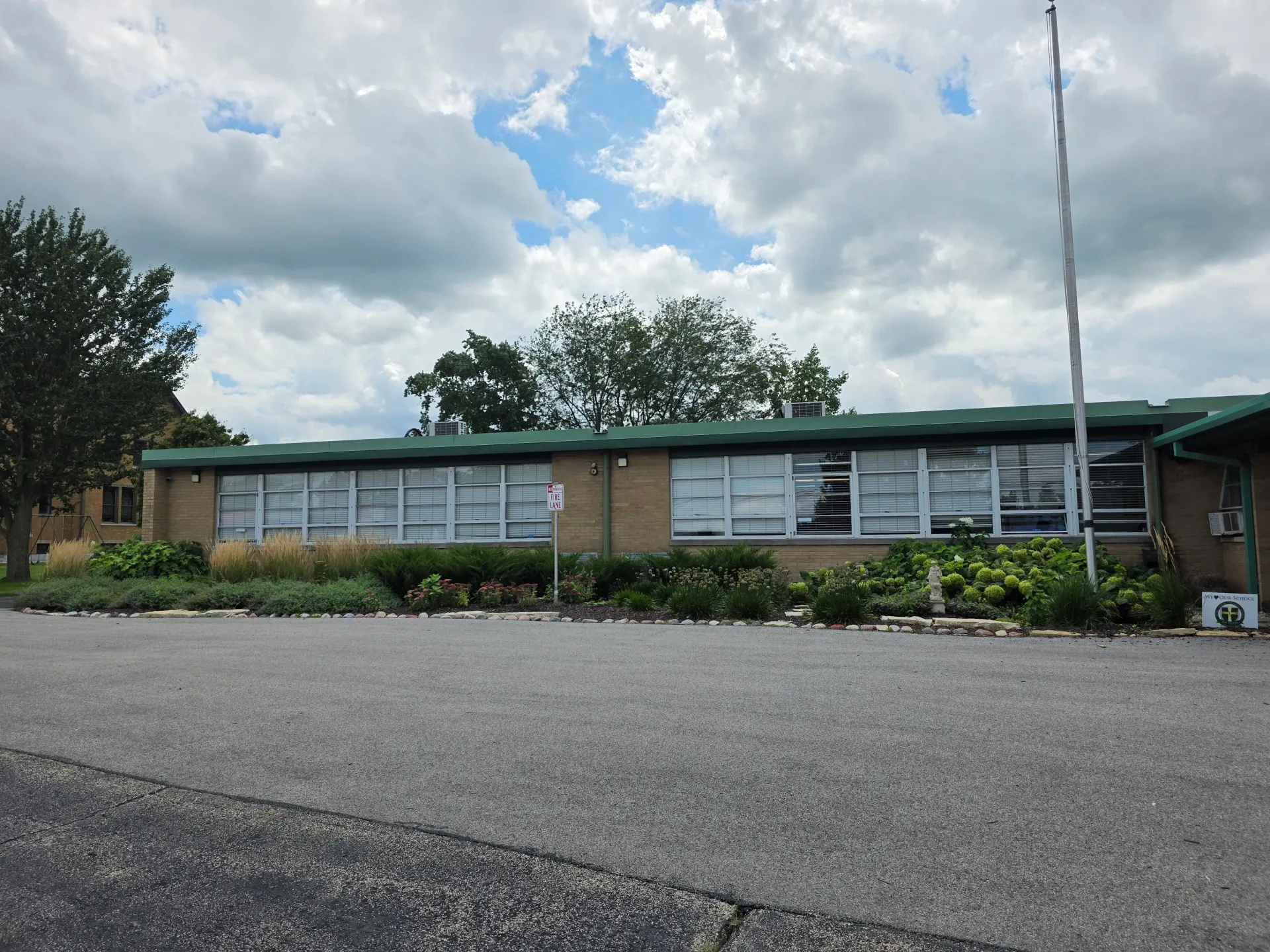 Low-rise commercial building with a long row of exterior windows beneath a cloudy sky.
